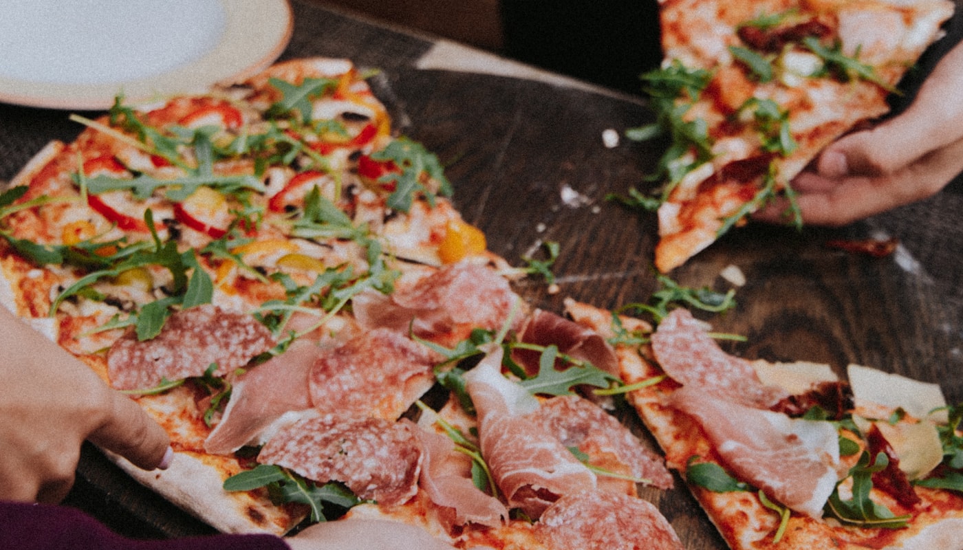Pizza in formato lungo tagliata in tranci su tavola di legno